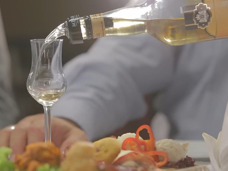 osoba sipa rakiju u duguljastu rakijsku čašicu